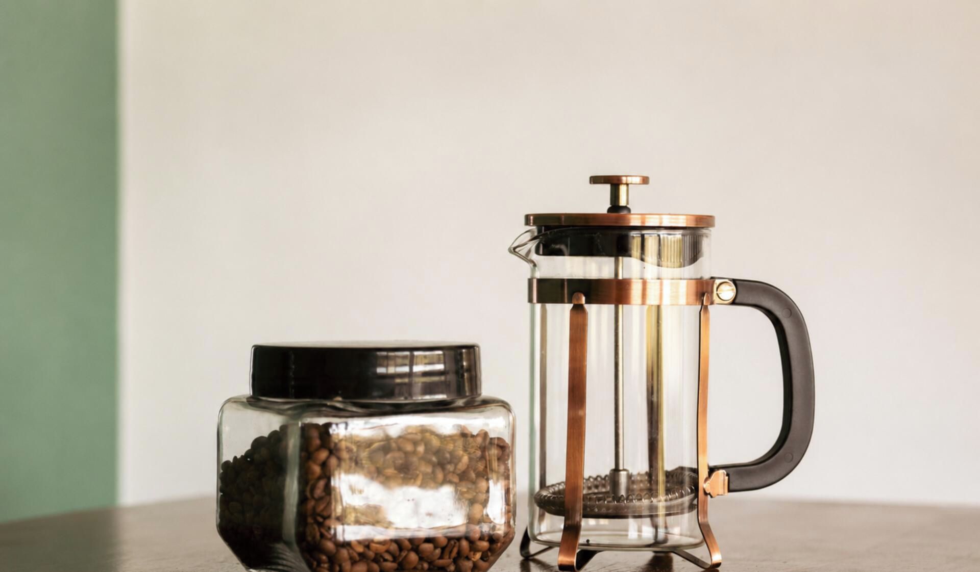 A French press coffee maker and a glass jar of coffee beans.