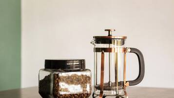 A French press coffee maker and a glass jar of coffee beans.