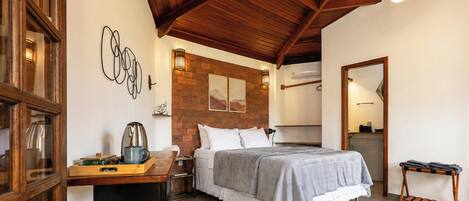 Un dormitorio con cama, un escritorio de madera, una cafetera y una pared de ladrillo.