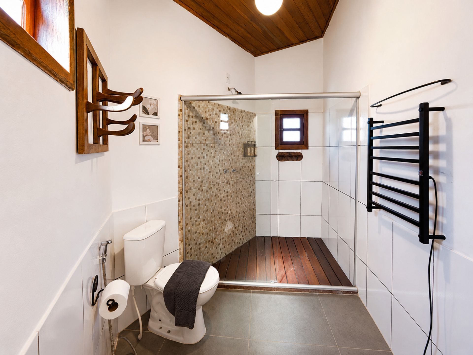 Casa de banho com chuveiro, sanita e porta-toalhas.