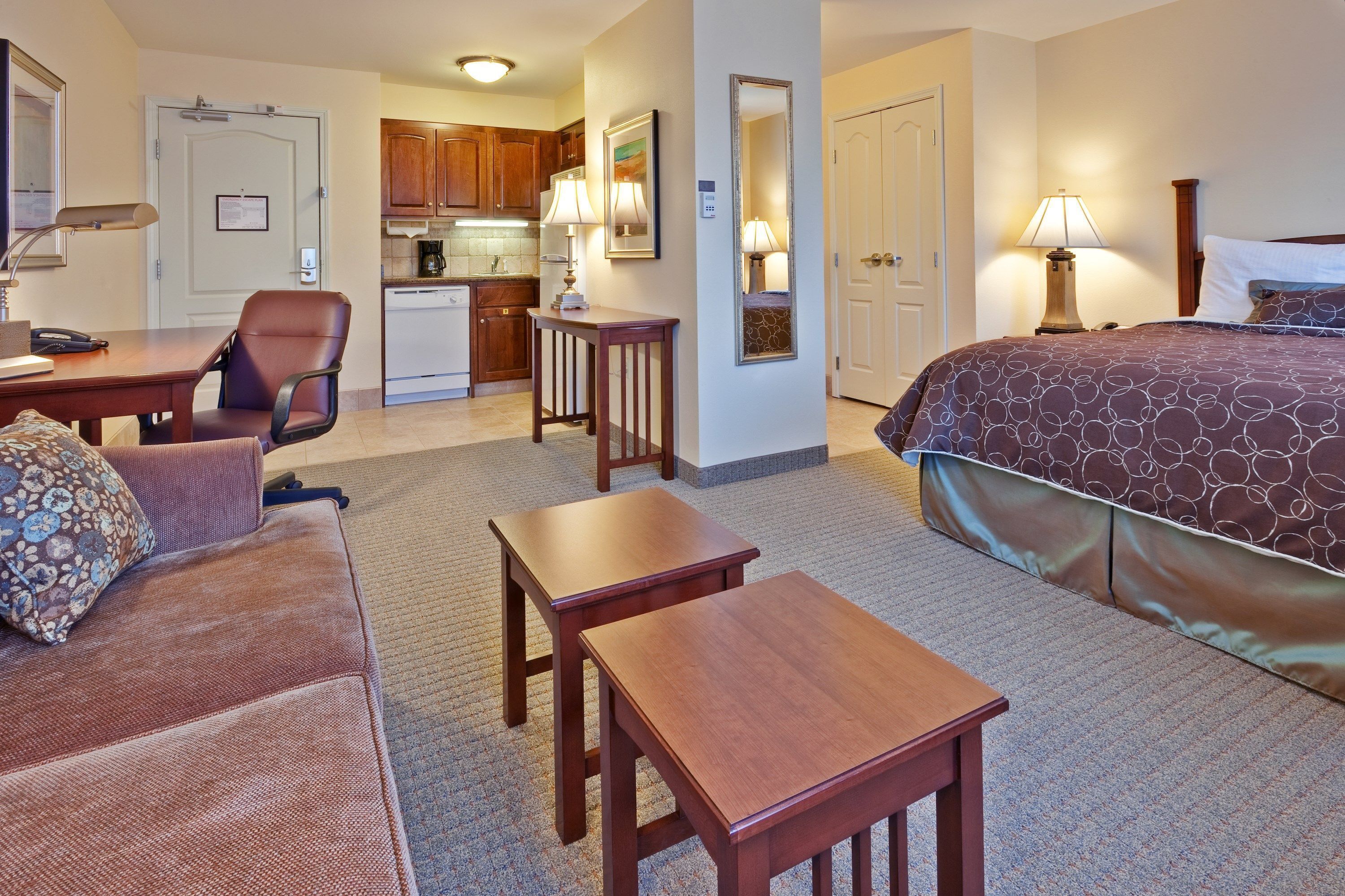 Une chambre d’hôtel comprenant un lit, un canapé, un bureau, une chaise, une petite table et un coin cuisine.