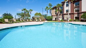 A swimming pool with lounge chairs and palm trees, surrounded by a building with multiple floors and balconies. - Free Breakfast | 1.5 Miles from Orlando International Airport + 25 Minutes to Disney World (Orlando)