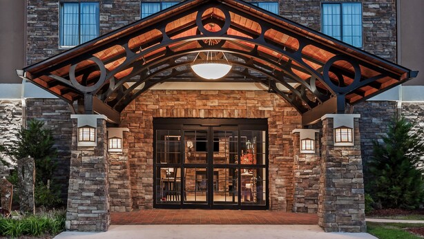 A hotel entrance with a stone facade, a wooden archway, and a large glass door. - Free Breakfast. Outdoor Pool. King Suite Close to the Convention Center (Fort Worth)