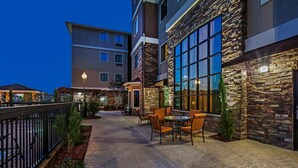A hotel courtyard with outdoor seating, stone walls, and large windows. - Free Breakfast. Outdoor Pool. King Suite Close to the Convention Center (Fort Worth)
