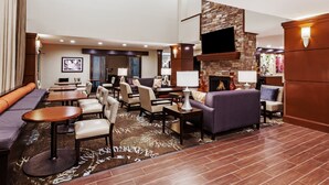 A spacious lobby with seating areas, a fireplace, and a flat-screen TV mounted on a stone wall. - Free Breakfast. Outdoor Pool. King Suite Close to the Convention Center (Fort Worth)