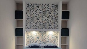 Ein Schlafzimmer mit einem Bett, einem gemusterten Kopfteil und integrierten Regalen.