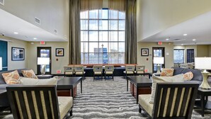 A hotel lobby with a large window, seating area, and exit signs.