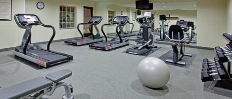 A gym with treadmills, a bench, a large exercise ball, and weight machines.