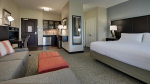 Habitación de hotel con una cama grande, un sofá, una pequeña cocina y un baño independiente.