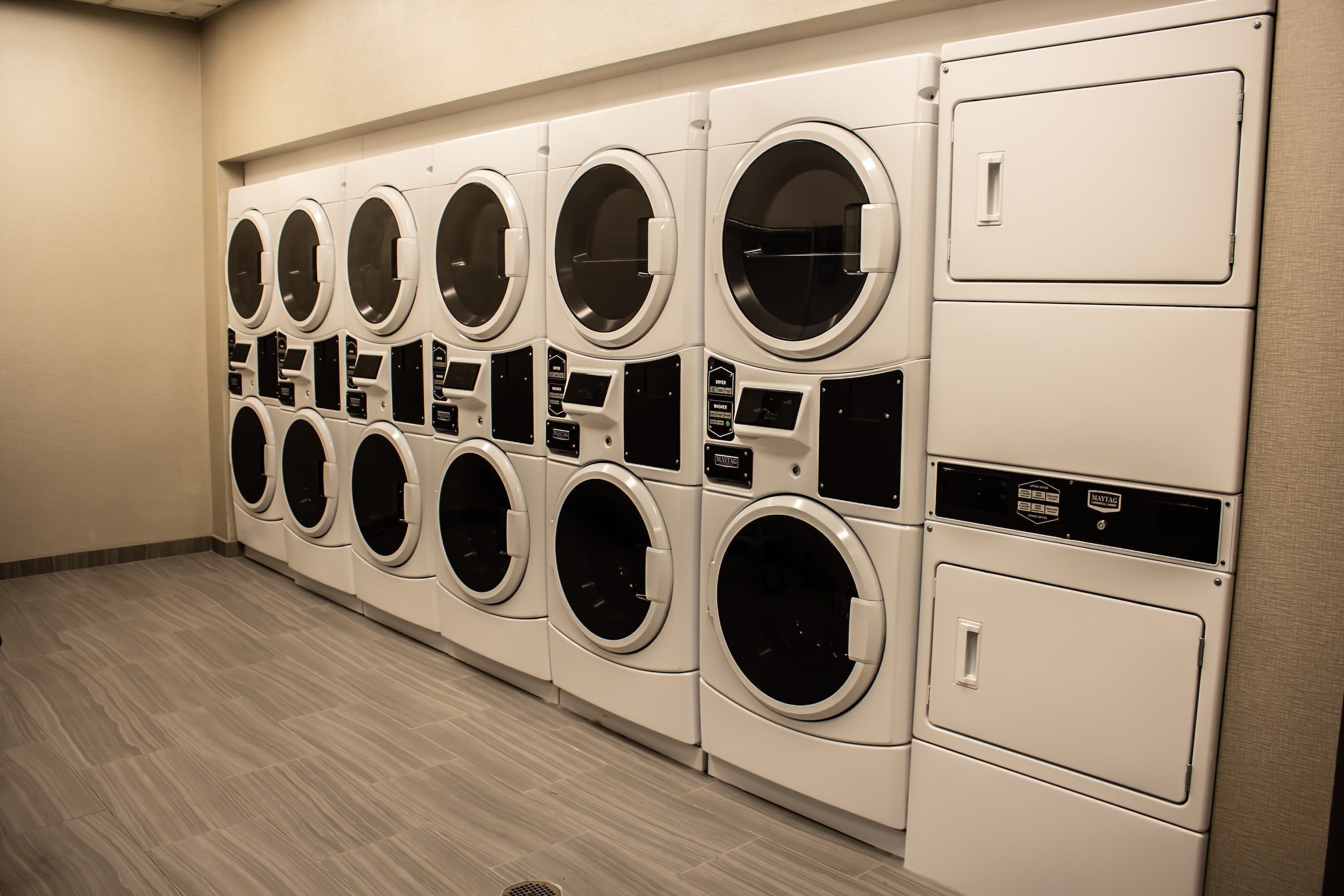 A row of white front-loading washing machines in a commercial setting.