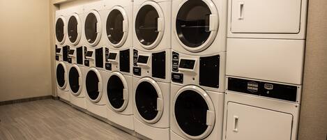 A row of white front-loading washing machines in a commercial setting.