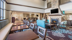 A spacious lobby with multiple seating areas, a fireplace, and a television mounted on a stone wall. - Perfect for Groups! | Pool + Gym + Free Breakfast (Newark)