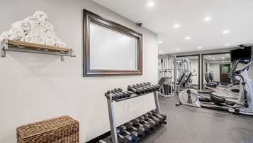 A gym with exercise equipment, towels, and a framed picture on the wall.