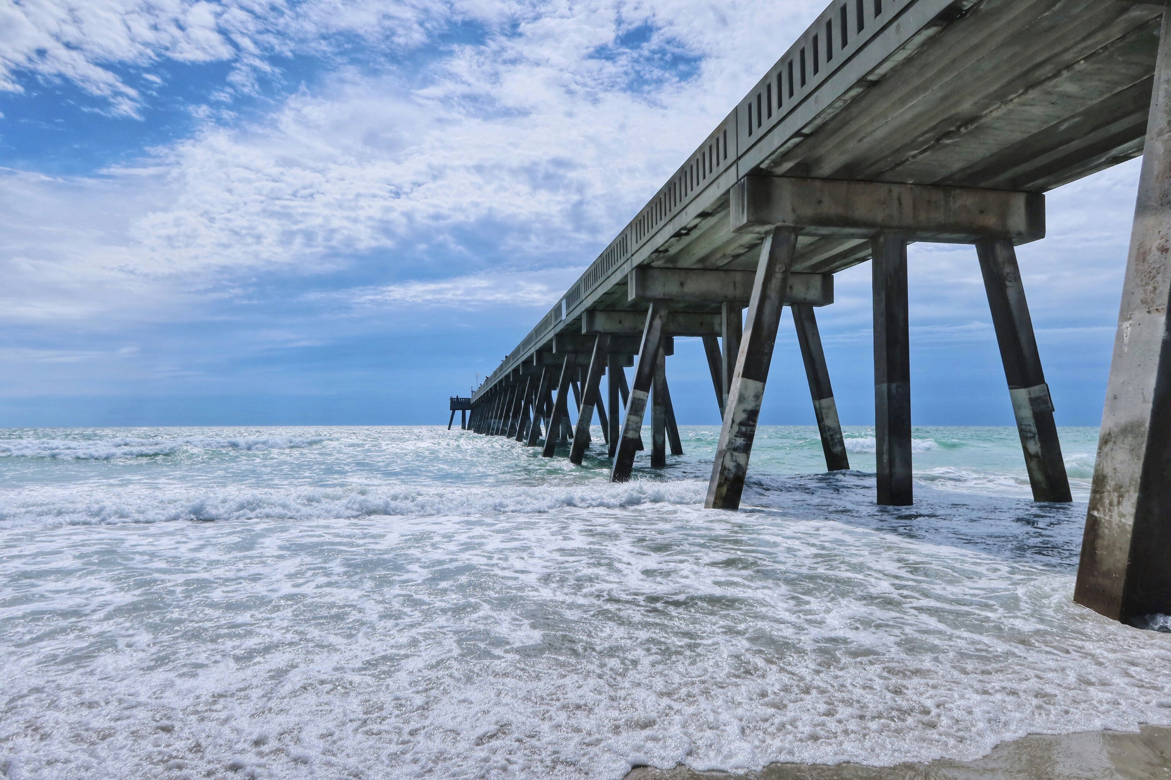 A pier extending into the ocean with waves crashing against it.