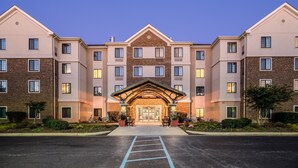 A multi-story hotel with a central entrance, a parking lot in front, and a clear sky. - Perfect for Groups! | Pool + Gym + Free Breakfast (Newark)
