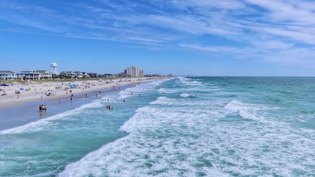 A beach with a water tower, beach umbrellas, and a hotel in the background. - Perfect for Groups! | Pool + Gym + Free Breakfast (Newark)