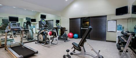 Une salle de sport équipée de tapis de course, de vélos elliptiques et de poids libres.