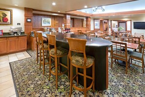 A spacious hotel lobby with a central bar area, multiple seating arrangements, and a patterned floor.
