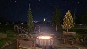 A night-time outdoor seating area with a fire pit, benches, and a view of the sky.