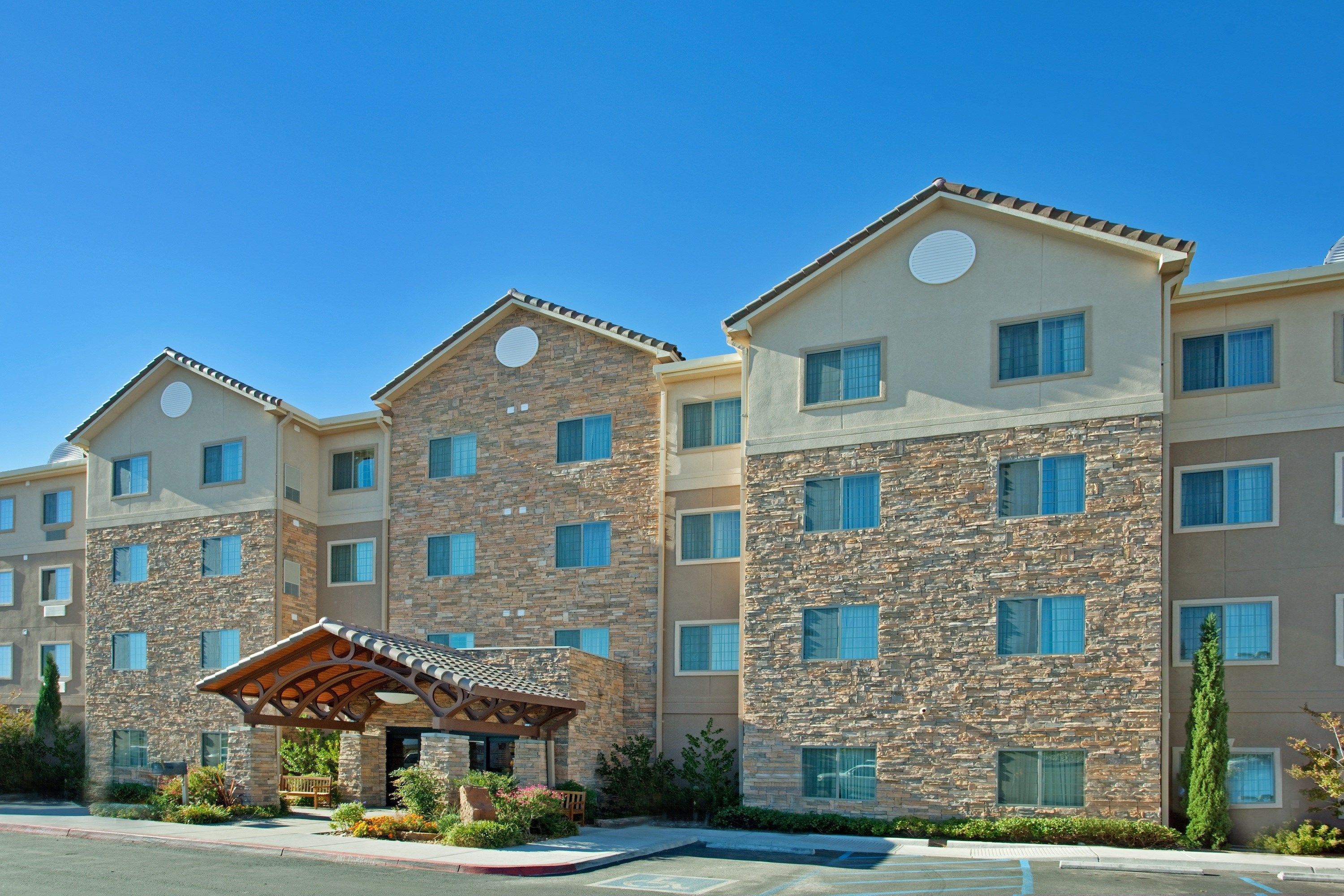A multi-story hotel with stone facade, multiple windows, and a covered entrance area.