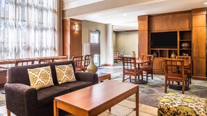 Un vestíbulo de hotel con un sofá, una mesa de centro y un área de comedor con sillas y un televisor.