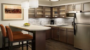 A modern kitchen with a central island, stainless steel appliances, and a tiled backsplash.