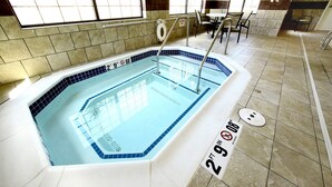 Une piscine intérieure rectangulaire, aux carreaux bleus, avec un poste de surveillance pour les sauveteurs et un panneau indiquant une profondeur de 2 pieds et 9 pouces.