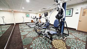 A gym with exercise equipment, carpeted floor, and a door.
