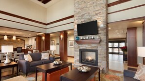 A spacious lobby with a fireplace, comfortable seating, and a flat-screen TV mounted on the wall.