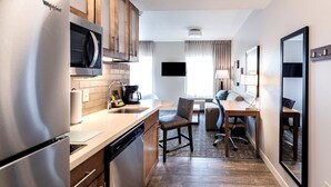 A compact kitchen with a built-in microwave, a coffee maker, and a dishwasher. There is a dining area with a table and chairs, and a large mirror on the wall. - Free Breakfast. Outdoor Pool. Gym. Close to Maxwell Air Force Base! (Montgomery)