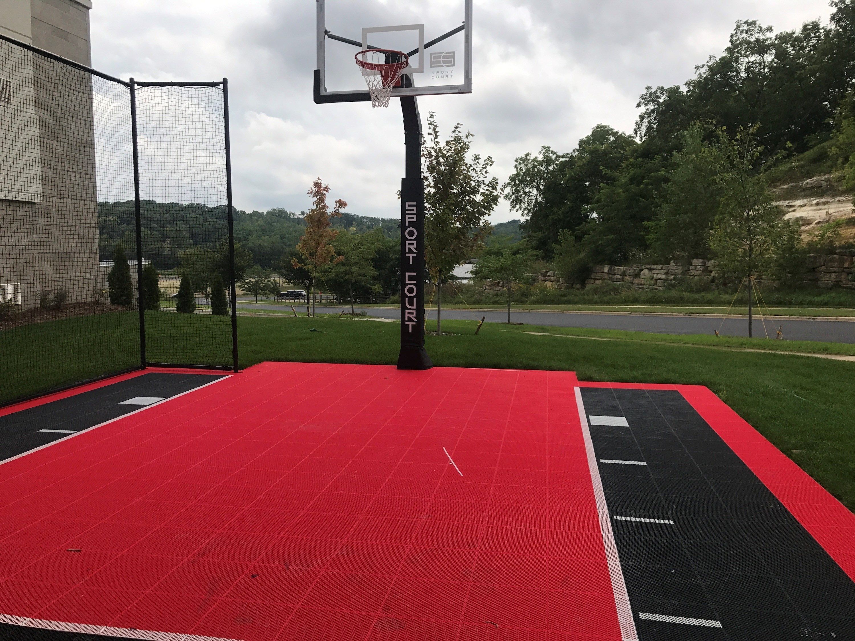 An outdoor basketball court with a red playing surface, a net, and a sign that reads "FORT COURT".