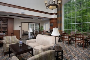 A spacious lobby with a large window, a sofa, chairs, a coffee table, and a chandelier. - Free Breakfast. Indoor Pool. Close to Rutgers University! (North Brunswick)