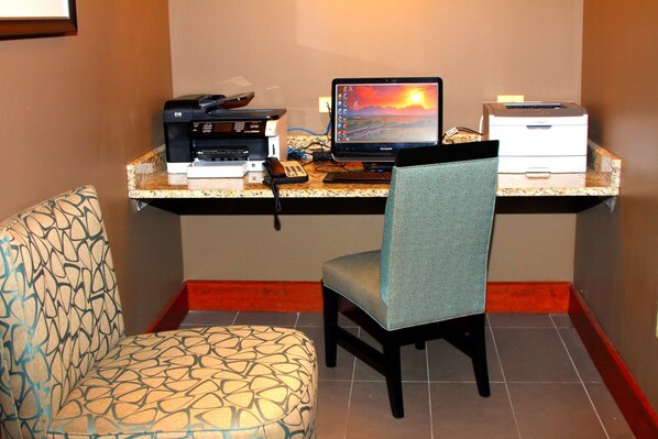 A workspace with a computer, printer, and telephone on a counter.