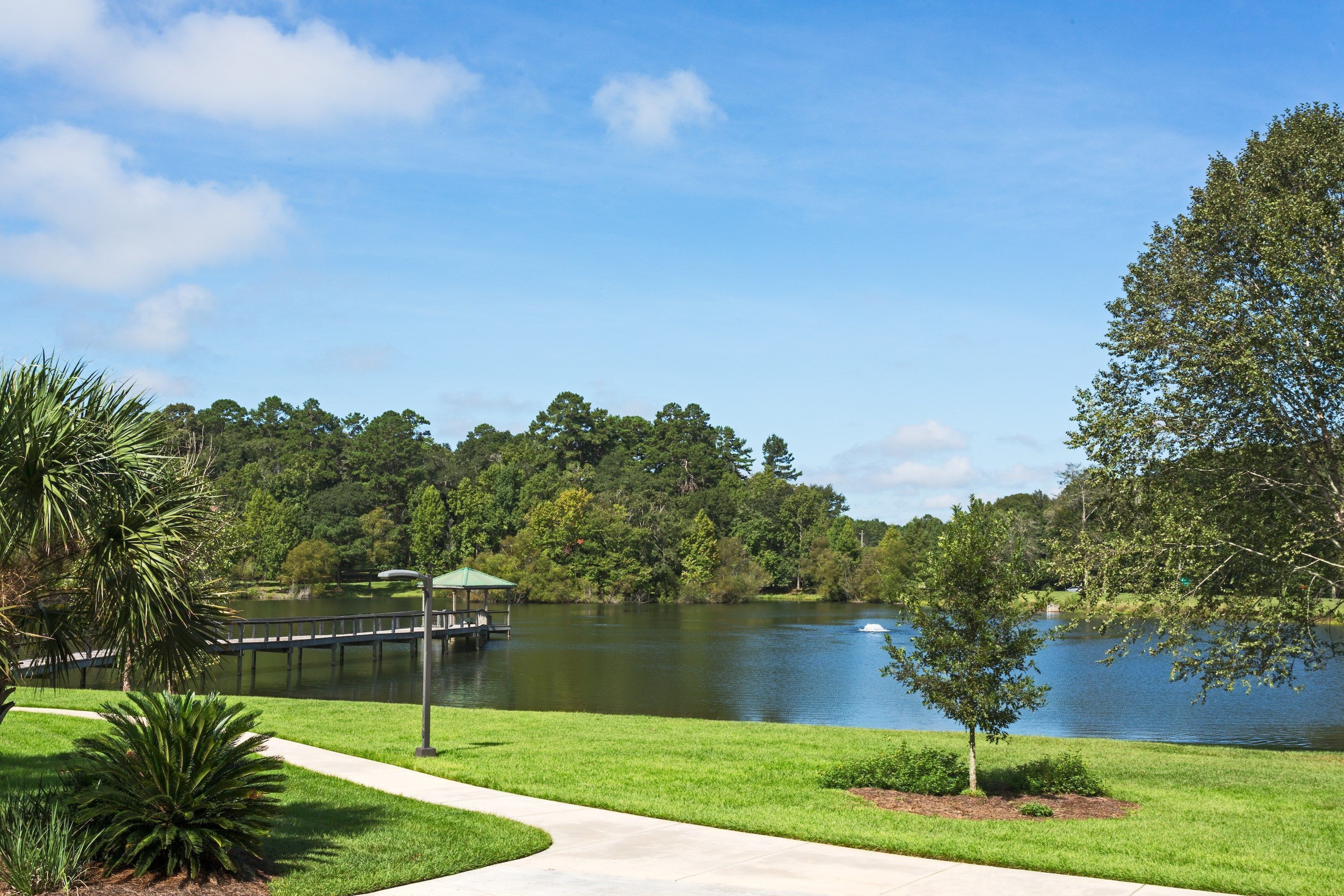 A lakeside view with a gazebo, grassy areas, and trees.