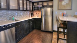 Una cocina moderna con armarios oscuros, un refrigerador de acero inoxidable, un microondas y un lavavajillas.
