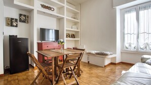 A modern living room with a wooden dining table, chairs, a TV, and a sofa. - Adorable flat near centre (Milan)
