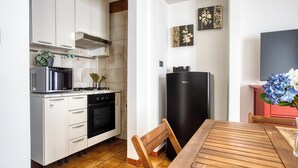 A compact kitchen with white cabinets, a black refrigerator, a stove, and a microwave. - Adorable flat near centre (Milan)