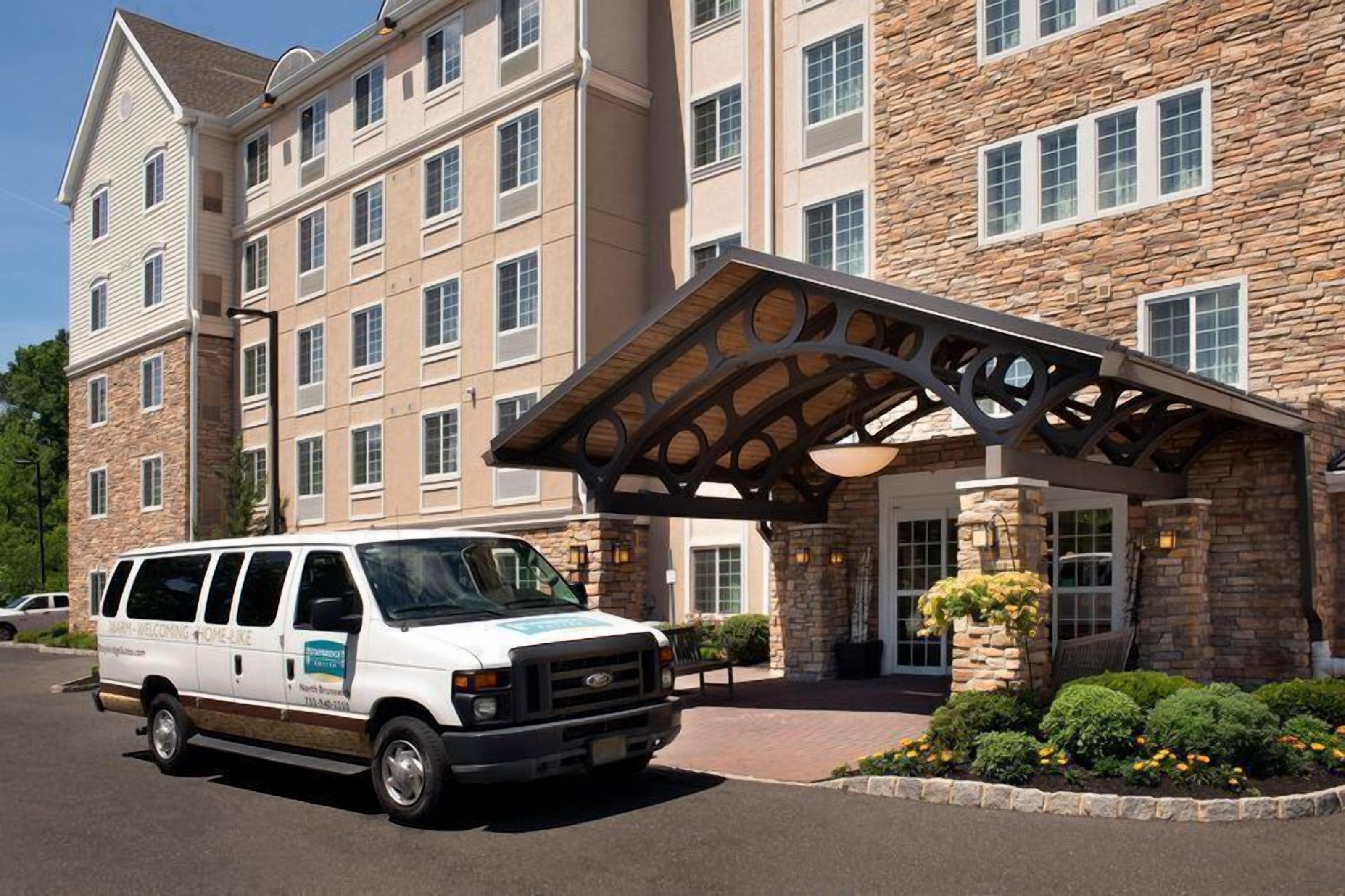 A multi-story hotel with a stone facade, a covered entrance, and a van parked in front.