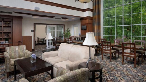 A spacious lobby with a large window, a sofa, a coffee table, and a dining area.