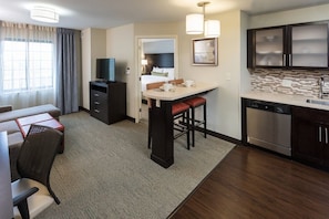 A modern hotel room with a kitchenette, a dining area, and a separate living space. - 1 Bedroom Suite | King Suite. Free Breakfast (Omaha)