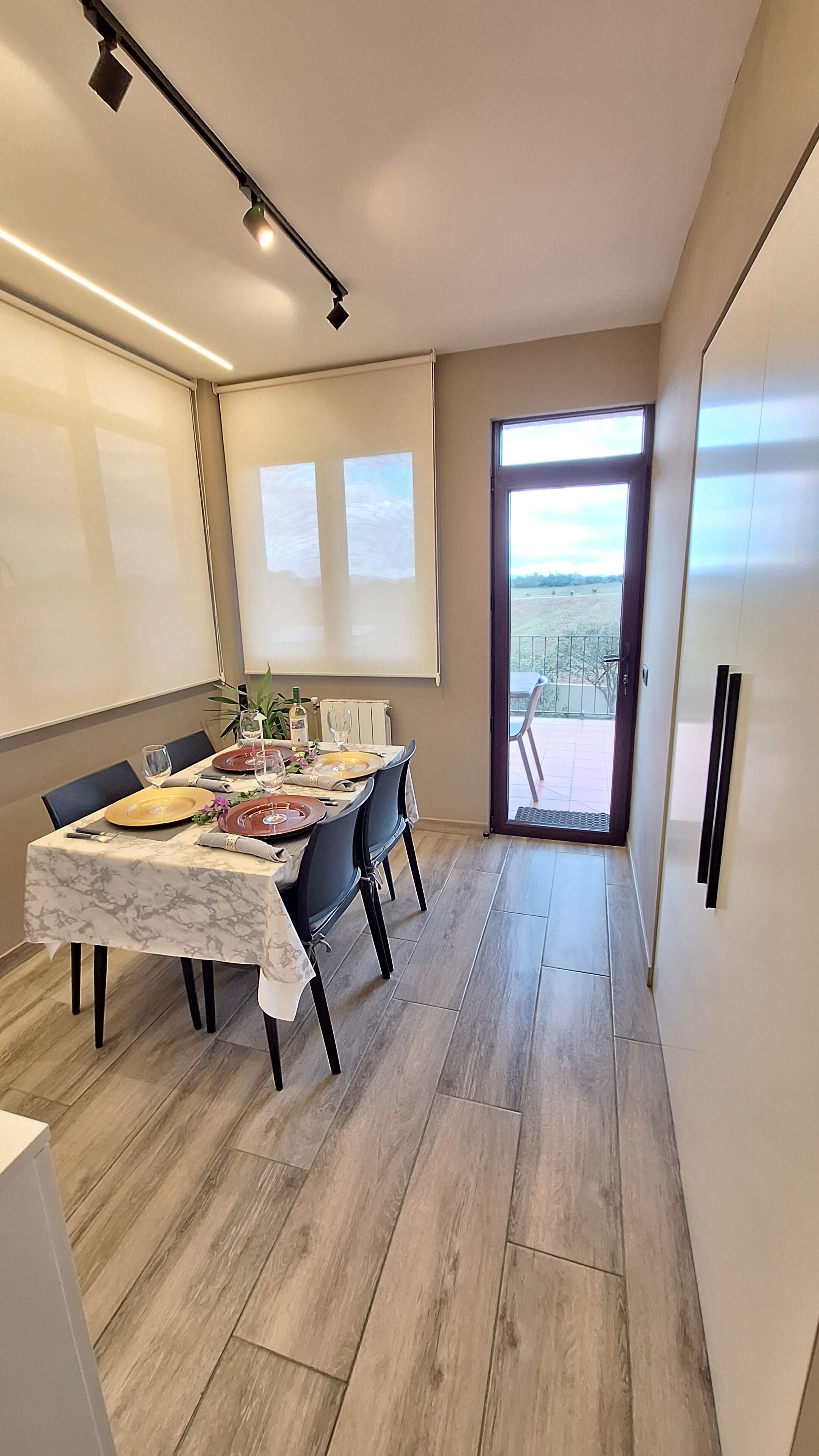 Un coin repas avec une table dressée pour quatre personnes, une vue sur l’extérieur et un aménagement intérieur moderne.