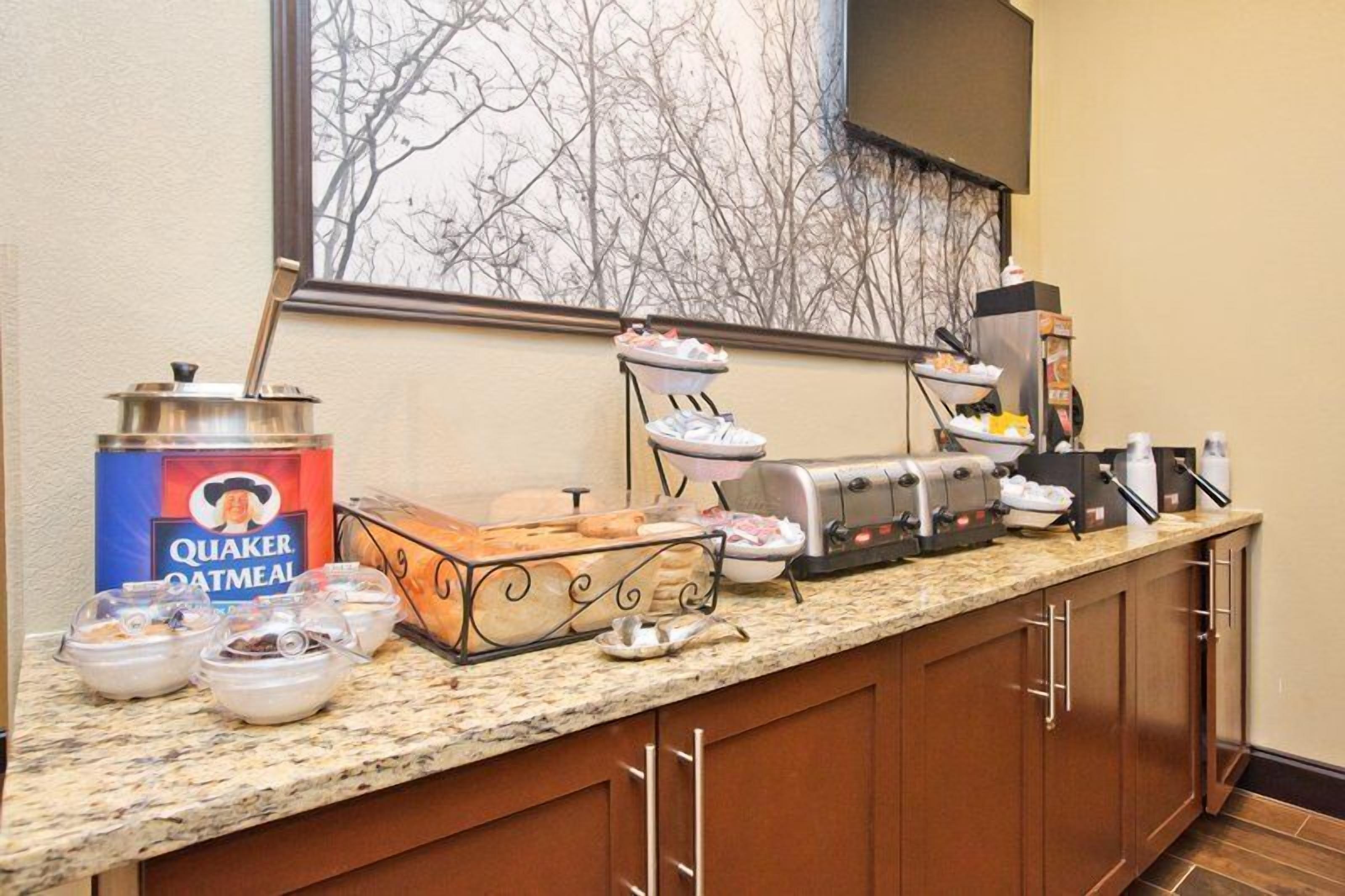 A breakfast buffet setup with Quaker Oatmeal, a toaster, and various food containers.
