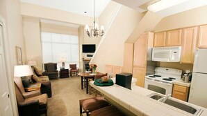 A compact kitchen with a microwave, stove, and sink. There is a dining area with a table and chairs. - Slopeside Location + Shared Outdoor Hot Tub (Kirkwood)