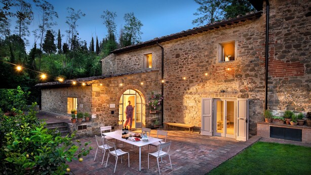 A stone building with a patio area, outdoor seating, and string lights. - L'orto Vignamaggio Private Pool Nature (Greve in Chianti)
