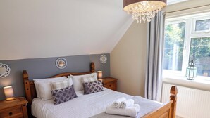 Ein Schlafzimmer mit einem hölzernen Bett, zwei Nachttischen, einem Fenster mit Vorhängen und einer Chandelier.