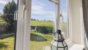 Ein Fenster mit Blick auf ein grünes Feld und einer dekorativen Laterne auf der Fensterbank.