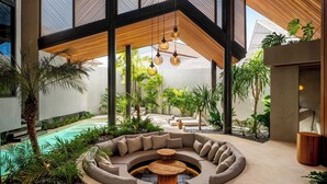 Un área lounge al aire libre moderna con piscina, mobiliario y plantas tropicales.