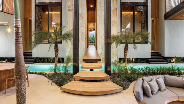 Un área de piscina interior moderna con una escalera de madera, asientos y vistas a la piscina.