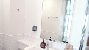 A modern bathroom with a white sink, a large mirror, and a toilet.