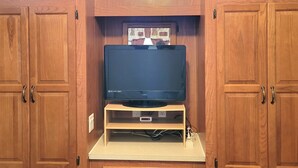 Un mueble de madera con un televisor de pantalla plana sobre un soporte, cajones debajo y una ventana arriba.
